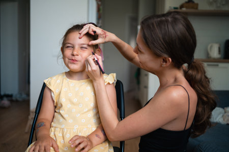 Close-up of makeup artist doing kids makeup with pink eyeliner. Small girl party or birthday day...