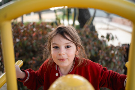Child girl on the playground climbing structures, outdoors free play of primary school