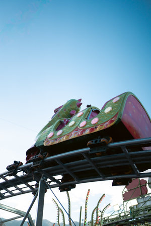A roller coaster cart in motion against a clear blue sky, captured from below.の写真素材