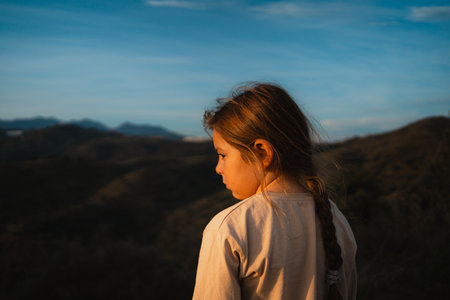 Close-up of young girl with braided hair, looking thoughtfully into the scenic horizon, embracing the tranquilityの写真素材