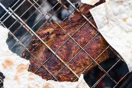 A close-up of perfectly seasoned grilled meat and flatbread on a barbecue grill, ready to be servedの写真素材