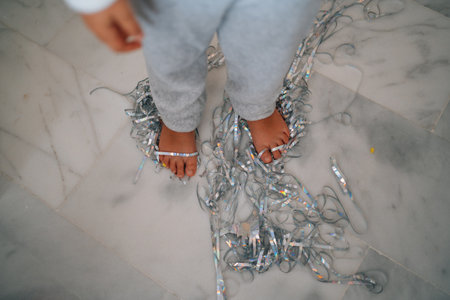 Child on marble floor with silver confetti ribbons