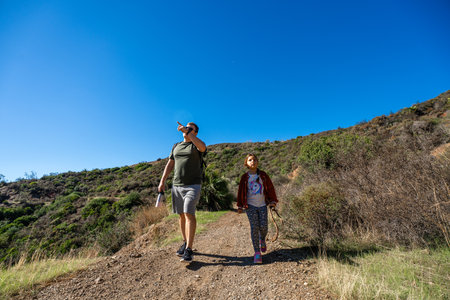 Caucasian male and young girl hiking on sunny mountain trailの写真素材