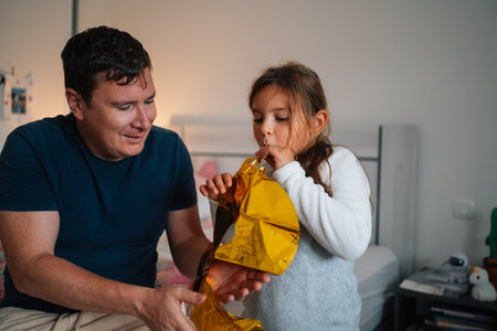 Caucasian adult male and child blowing balloon indoorsの写真素材