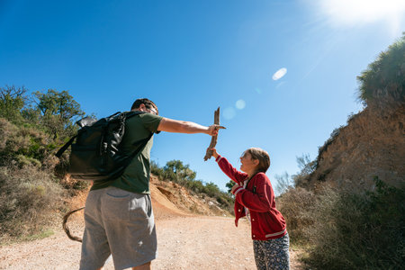 Caucasian male adult and young girl playing with sticks on sunny nature trailの写真素材