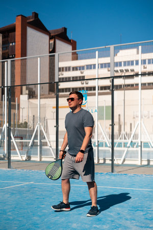 Man playing padel on a sunny urban court.の写真素材