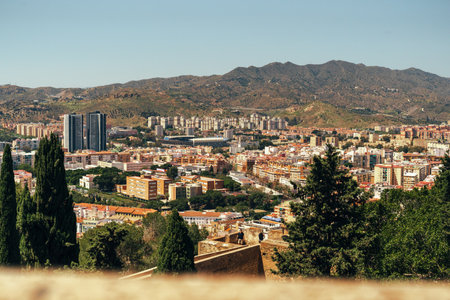 Cityscape with mountains, urban architecture, and lush greenery.の写真素材