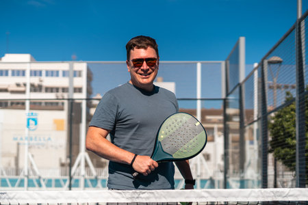 Man enjoying a sunny day of padel tennis on an outdoor court.