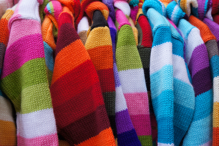 Colorful striped pullovers on hangers.の写真素材