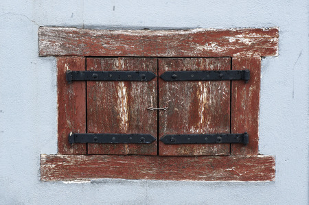 Old ancient window closed with wooden shutters in wall of medieval hose in Vilnius, Lithuania.