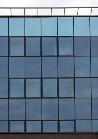 Glazed wall and windows of modern building. Abstract vertical blue architectural background.の写真素材