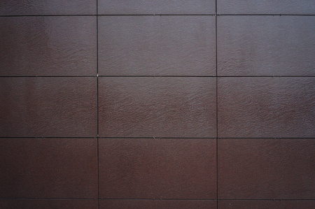 Wall coated with facing panels. Abstract dark brown texture and architectural background.