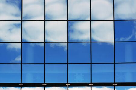 Reflections of blue sky and white clouds in big windows of modern building. の写真素材