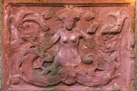 Ancient stone bas-relief of mermaid with two tails on a wall of medieval building in Wurzburg, Germany.のeditorial素材