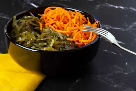 Sea kale Laminaria and pickled carrot in black bowl. Vegan asian seafood. Selective focus.の写真素材