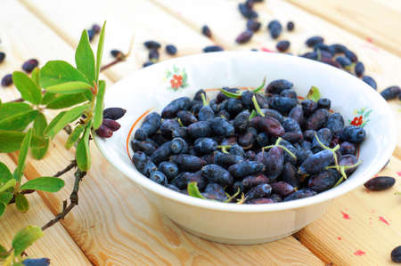 Fresh Ripe Honeysuckle Berries in Bowl on Wooden Table.