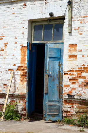 Weathered Timeworn Shabby Wooden Door Entrance to Old Brick Building.の写真素材