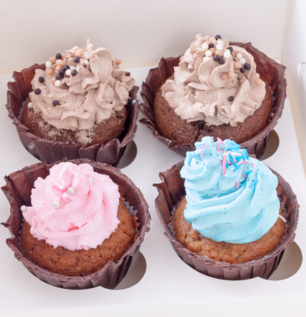 Four different cupcakes with icing in white boxの写真素材