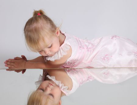 Beautiful blonde young girl looking in the mirror, studio shotの写真素材