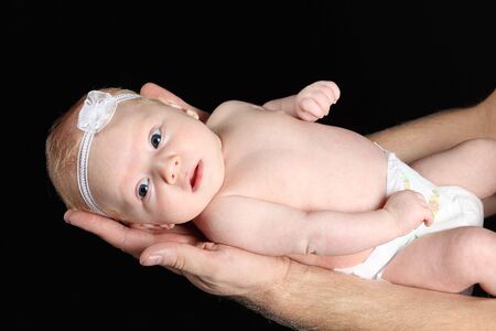 Father holding a cute 2 months old girl baby, studio shot