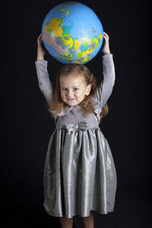 Beautiful girl standing with globe, studio shotの写真素材