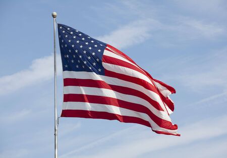 Photo of American flag waving in the wind on blue sky