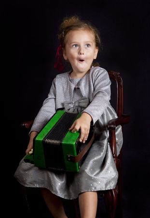 Beautiful young girl with accordion singing on black isolatedの写真素材