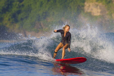 picture of girl surfing a wave in Indonesia.Lombok island.の写真素材