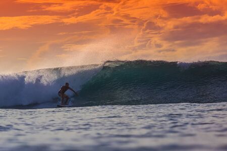 Surfer on Amazing Wave at sunset time, Bali island.の写真素材
