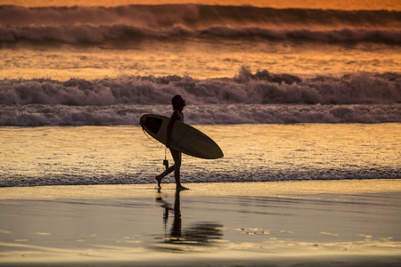 Surfer on the Beach at Sunset Tme, Bali, Indonesiaの写真素材