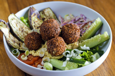 Vegetarian falafels and vegetables in bowl on white wood の写真素材