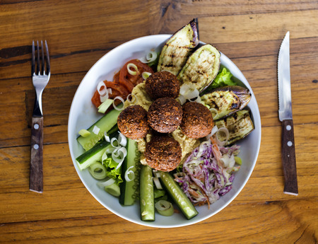 Vegetarian falafels and vegetables in bowl on white wood 
の写真素材