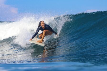Female surfer on a blue wave at sunny dayの写真素材
