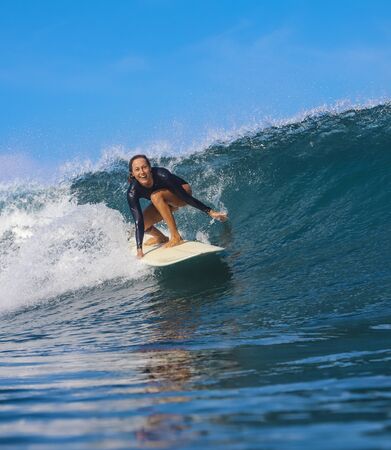 Female surfer on a blue wave at sunny day