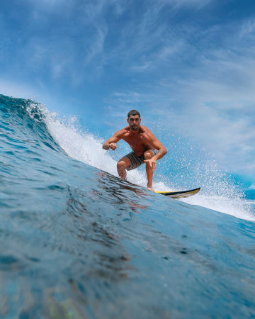 Male surfer on a blue wave at Bali islandの写真素材