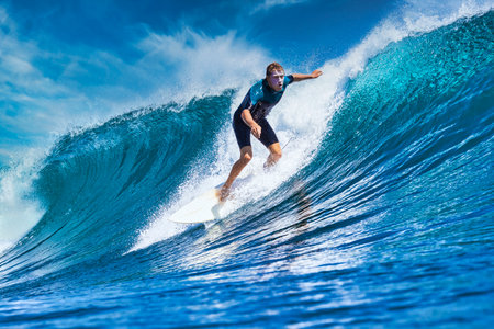 Male surfer on a blue wave at sunny dayの写真素材