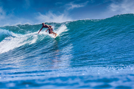 Male surfer on a blue wave at sunny dayの写真素材