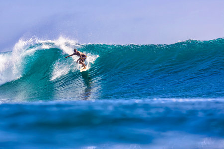 Male surfer on a blue wave at sunny dayの写真素材