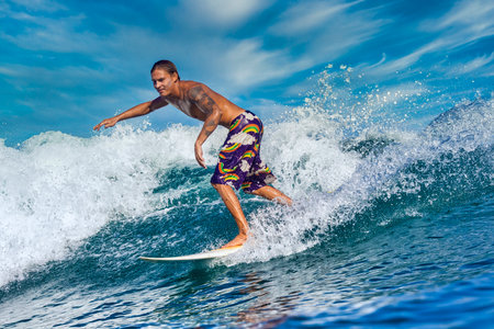 Male surfer on a blue wave at sunny day