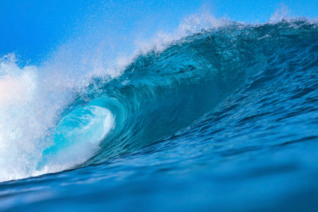 Massive blue ocean wave curling, bright turquoise barrel breaking with foamy crest and spray, sunlightの写真素材
