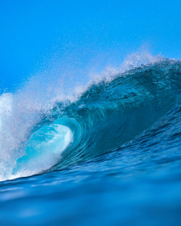 Massive blue ocean wave curling, bright turquoise barrel breaking with foamy crest and spray, sunlightの写真素材