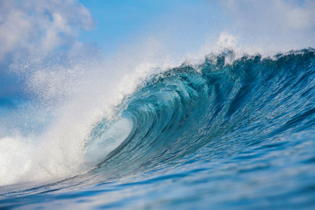 Massive blue ocean wave curling, bright turquoise barrel breaking with foamy crest and spray, sunlightの写真素材