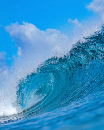Massive blue ocean wave curling, bright turquoise barrel breaking with foamy crest and spray, sunlightの写真素材