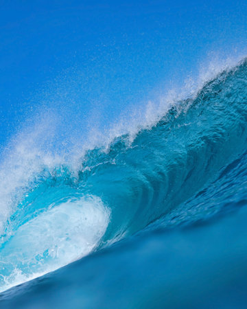 Massive blue ocean wave curling, bright turquoise barrel breaking with foamy crest and spray, sunlightの写真素材
