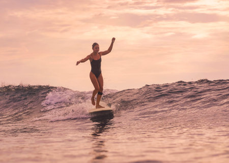 Woman Smiling While Riding Small Wave In Golden Light, Upbeat Expression And Relaxed Posture, Warm Tonesの写真素材
