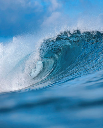 Massive blue ocean wave curling, bright turquoise barrel breaking with foamy crest and spray, sunlightの写真素材