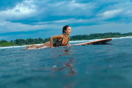 Young Woman Practicing PopUp Technique On Board With Joyful Expression, Coastal Lesson And Steady...