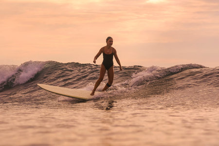 Woman Gliding Down Smooth Wave Face At Sunset, Forward Focus And Confident Footwork, Clean Water...