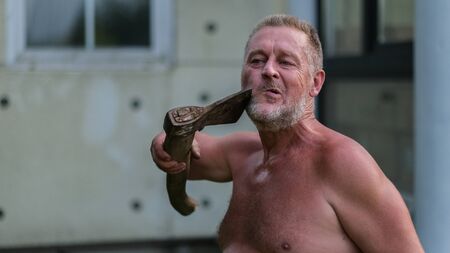 Brutal man shaves with an axe at the cottage