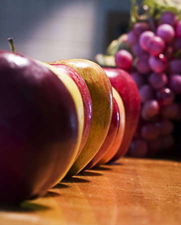 Line up of apples with grapes in the backroundの写真素材